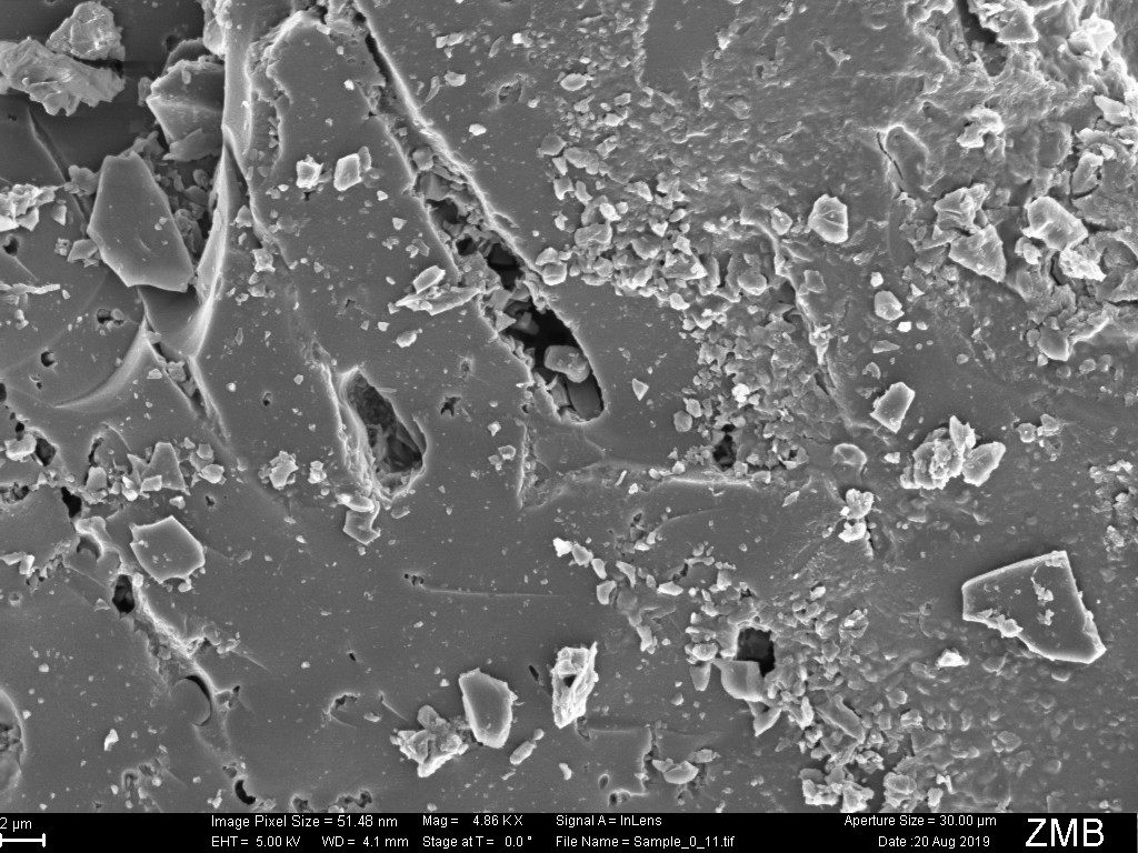 Scanning electron micrograph of untreated coconut charcoal at 4.86 KX, showing a mostly closed surface with sparse pores